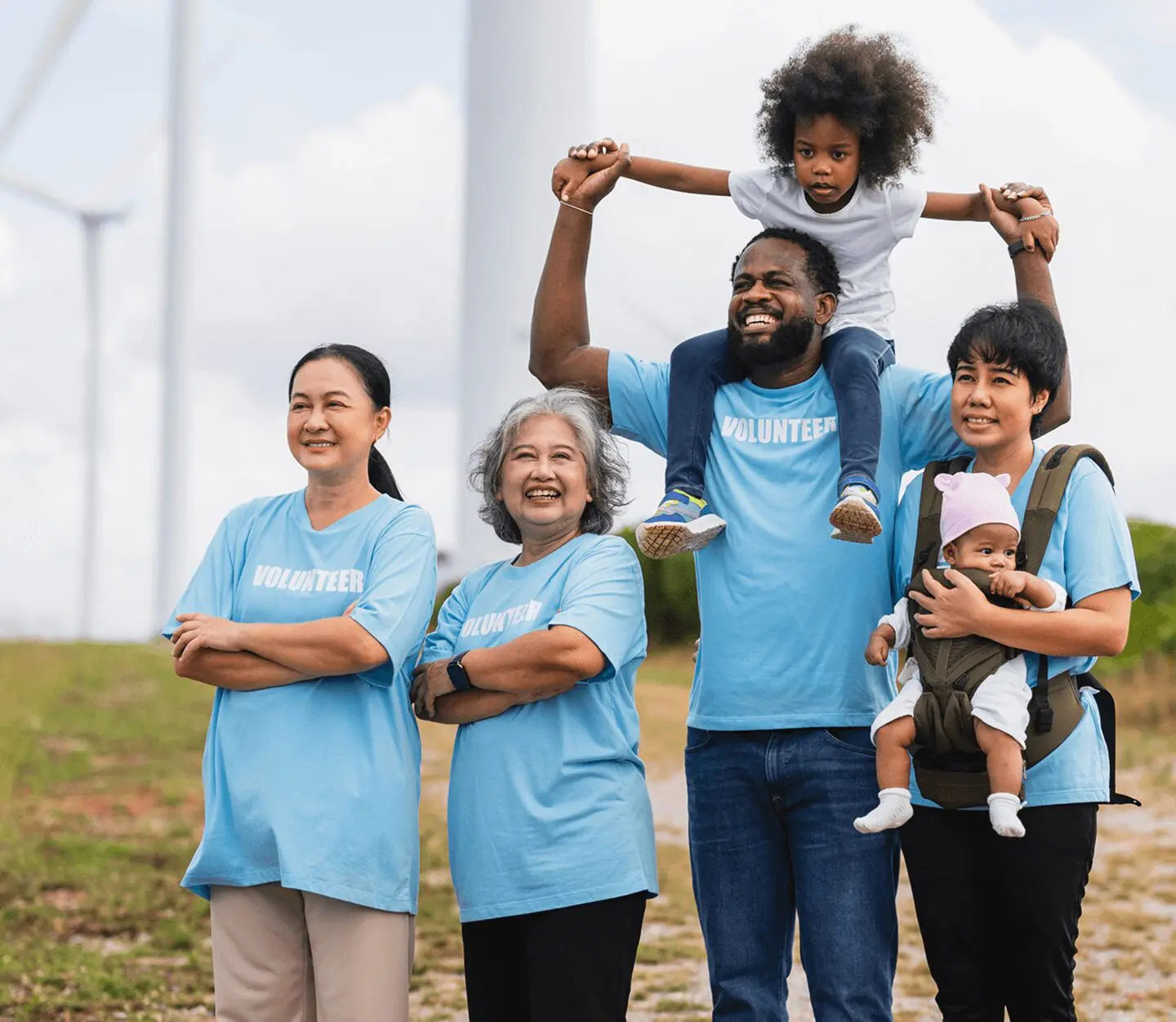 Group of volunteers smiling near wind turbines.